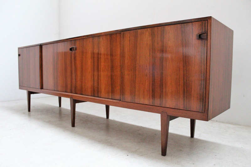 "Enfilade Vintage Scandinave En Palissandre De Rio Henry Rosengren Hansen"Exceptionnelle enfilade scandinave en palissandre de Rio, modèle 49, par Henry Rosengren Hansen. Ce meuble de grandes dimensions ouvre par quatre portes coulissantes découvrant des tiroirs et des tablettes coulissantes en partie centrale et des étagères de chaque côté. Meuble entièrement restauré et reverni par notre ébéniste partenaire. 240 X 80 X 46 cms. 7500€